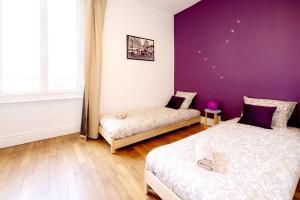 a bedroom with two beds and a purple wall at Spacieux T3 centre ville in Montluçon