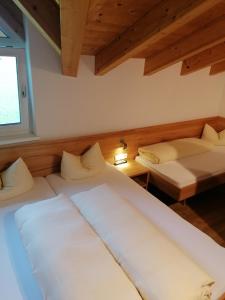 2 Betten in einem Zimmer mit Holzdecken in der Unterkunft Apart Stella Alpina in Pettneu am Arlberg