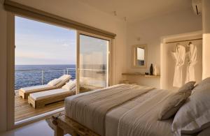 a bedroom with a bed and a balcony with the ocean at Infinity Villa milos in Pachaina