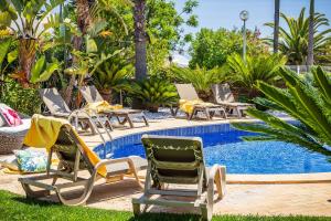 a group of lawn chairs next to a swimming pool at Villa Eva by OCvillas in Albufeira