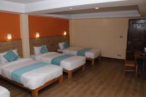 Habitación de hotel con 3 camas y mesa en Peshal Home, en Katmandú