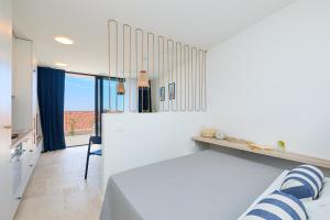 ein weißes Schlafzimmer mit einem Bett und einem Fenster in der Unterkunft Hedera Estate Hedera Studio 1 in Dubrovnik