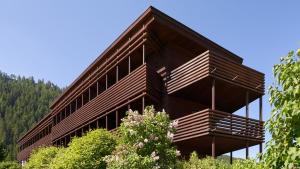 duży budynek z drewnianymi balkonami na szczycie drzew w obiekcie Saleghes Dolomites Residence w mieście Selva di Val Gardena