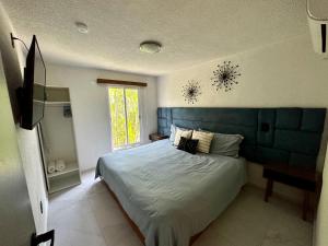a bedroom with a bed with a blue headboard and a window at CORMORAN COZY CONDO IN IXTAPA in Ixtapa