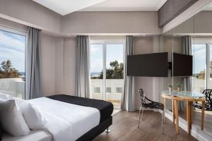 a hotel room with a bed and a table and a window at Kreoli Suites Glyfada in Athens