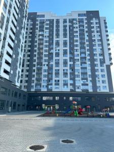 un gran edificio de apartamentos con un parque infantil delante de él en Loft Aparts, en Chişinău