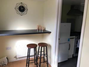 a kitchen with two bar stools next to a counter at The Annex in Ottery Saint Mary