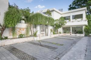 an exterior view of a white building with trees at Awila Villas Kuta in Legian