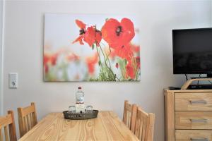 a dining room table with a picture of red flowers at Sandwig-Lodge in Glücksburg