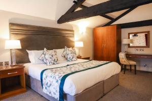 a bedroom with a large bed with a wooden headboard at Hazlewood Castle & Spa in Tadcaster