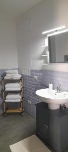 een badkamer met een wastafel, een spiegel en handdoeken bij Ballarhouse an elegant apartment in Palermo
