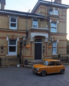 a small orange car parked in front of a house at The Victorian lodge in Ryde