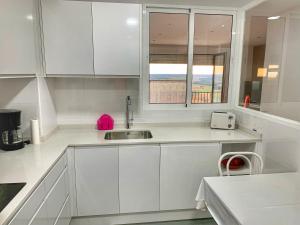 a white kitchen with a sink and a window at El Carmen in Toro +24 photos