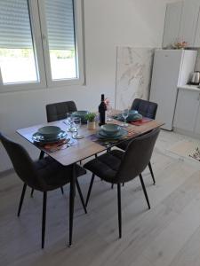 a dining room table with chairs and a bottle of wine at Knežević apartman in Podgorica