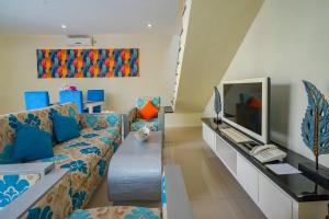 Awila Villas Kuta في ليغِيان: غرفة معيشة مع أريكة وتلفزيون