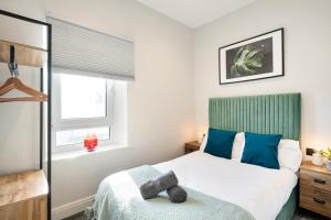 um quarto com uma cama com almofadas azuis e uma janela em Cosy Modern Apartment With Free Parking em Cardiff