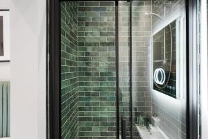 uma porta de duche envidraçada com uma parede de tijolos em Cosy Modern Apartment With Free Parking em Cardiff