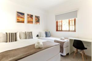 a white bedroom with two beds and a desk at Pousada Recanto do Jabaquara in Paraty