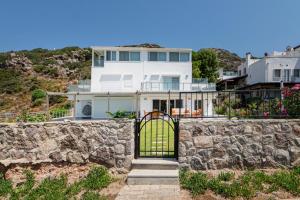 uma casa branca com uma parede de pedra e um portão em Villa w Pool Garden Patio 1 min to Beach in Bodrum em Yalıkavak