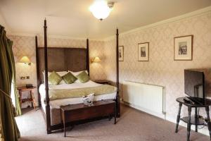 sypialnia z łóżkiem z baldachimem i telewizorem w obiekcie Hazlewood Castle & Spa w mieście Tadcaster