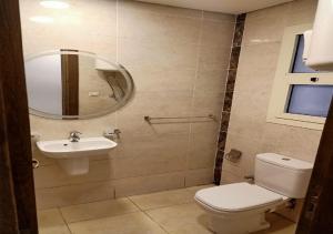 ein Badezimmer mit Toilette, Waschbecken und Spiegel in der Unterkunft Spacious 2Bdrs duplex in Porto new Cairo in Kairo + 5 Fotos