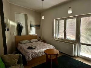 een slaapkamer met een bed, een tafel en 2 ramen bij Apartament Starówka in Zielona Góra