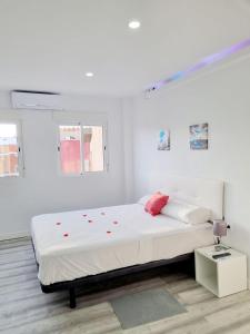 a white bedroom with a large bed with red accents at Apartamentos T5 Valencia in Torrent