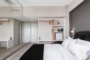 1 dormitorio con cama blanca y pared de cristal en Kreoli Suites Glyfada, en Atenas