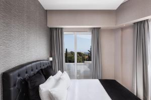 a bedroom with a bed and a large window at Kreoli Suites Glyfada in Athens