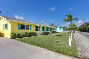 ein gelbes Haus mit blauem Trimm auf einer Straße in der Unterkunft Coastal Townhome with Patio about 2 Mi to Beach! in North Palm Beach