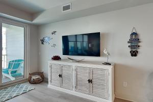 a living room with a television on a white cabinet at Sea Glass #211 in Gulf Shores