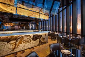 a restaurant with a bar with tables and chairs at The Westin Jakarta in Jakarta