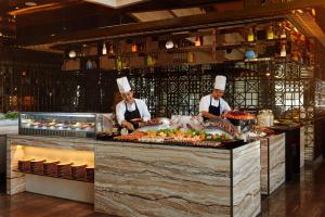 two chefs in a kitchen preparing food in a restaurant at The Westin Jakarta in Jakarta