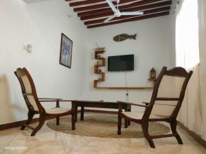 a dining room with two chairs and a table and a tv at Manama Suites Apartment in Lamu