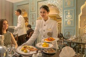 una mujer sosteniendo un plato de comida en un restaurante en Heritage Village Resort & Spa Manesar-Gurgaon, en Gurgaon