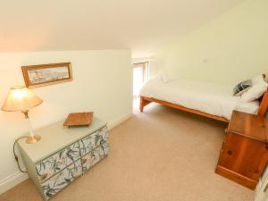 ニューポートにあるGarstons Barnのベッドルーム1室(ベッド1台、ランプ付きテーブル付)