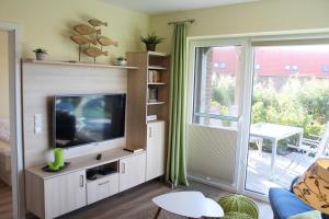 a living room with a television and a sliding glass door at LM 9-1-1 - Ferienwohnung Wremer Bogen Komfort in Schottwarden
