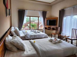 two beds in a hotel room with a window at Semilir Inn Senggigi in Senggigi 