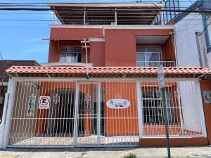 ein rotes Gebäude mit einem Tor davor in der Unterkunft Casa de Lis Hotel & Tourist Info Centre in Turrialba