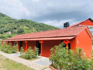 um edifício vermelho com um telhado vermelho e alguns arbustos em Prashiddha Resort em Dakshīnkāli