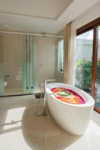 a bathroom with a large tub with a painting on it at Anari Villas Kuta in Legian