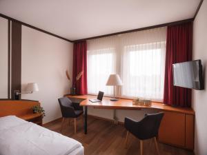 a hotel room with a desk and a bed at Mühlenhotel Halle-Leipzig in Landsberg