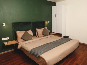 ein Schlafzimmer mit einem großen Bett und einer grünen Wand in der Unterkunft Qotel Hotel La Serene Gagan Vihar Near Preet Vihar Metro Station-Couple Friendly in Neu-Delhi