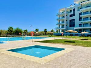 a swimming pool in front of a large building at Camaleones, Isla Canela - by AC REAL in Isla Canela