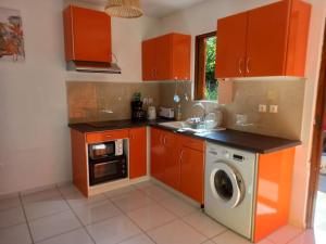 eine Küche mit orangefarbenen Schränken und einer Waschmaschine in der Unterkunft Bungalow Abricot in Petit-Bourg