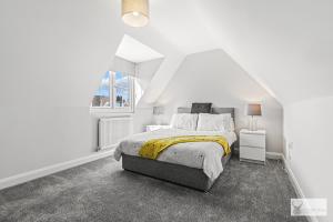 a white bedroom with a bed and a window at Elegant 5-Bed House with ample parking in Smisby