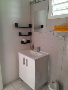 W białej łazience znajduje się umywalka i lustro. w obiekcie Bungalow Abricot w mieście Petit-Bourg