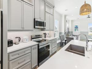 a kitchen with white cabinets and a sink at Sandy Smiles in Galveston +15 photos