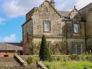 un viejo edificio de piedra con un árbol delante de él en The Pavillion en Carlisle