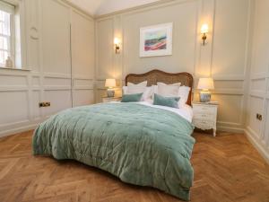 una camera da letto con un grande letto con una coperta verde di The Pavillion a Carlisle